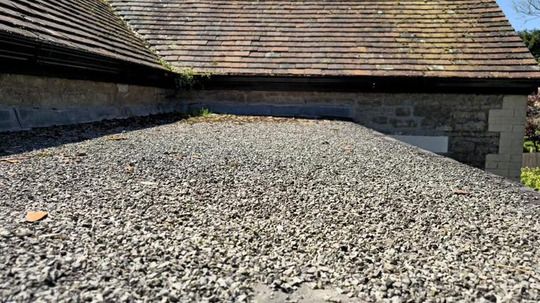 Before: ageing bitumen felt flat roof covered in loose gravel chippings in Somerset
